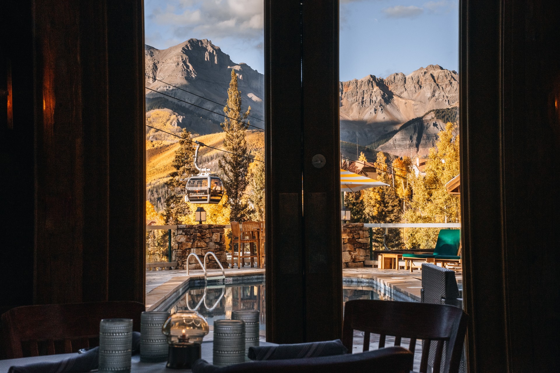 a view of a pool from a room with a cable car and mountains in the background