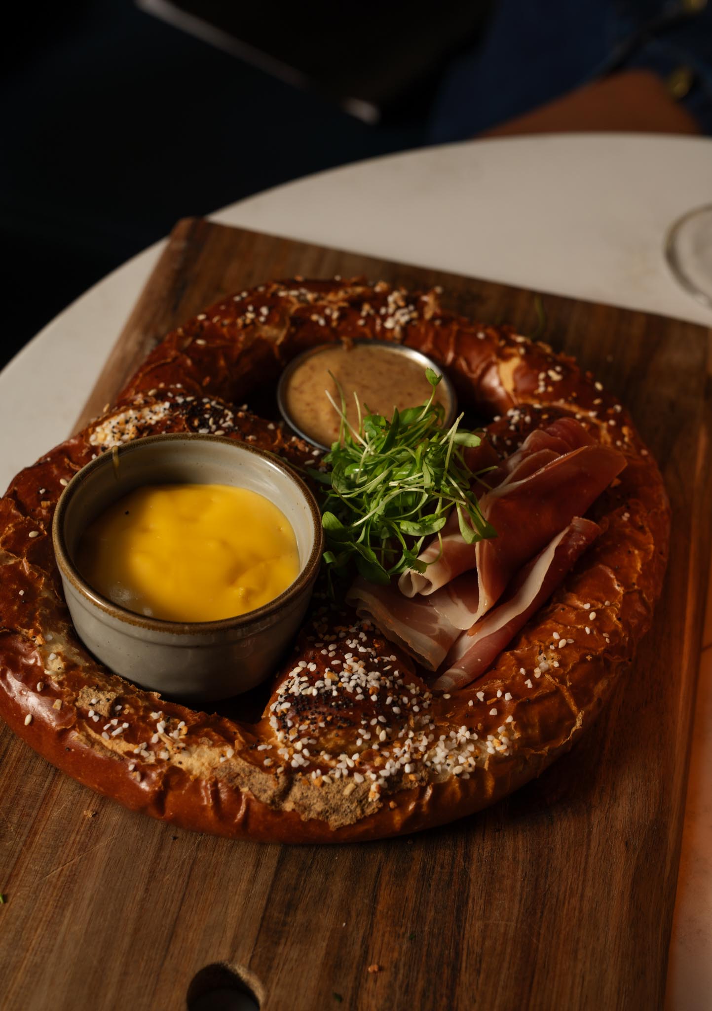 a pretzel with sauces and meat on a wooden board