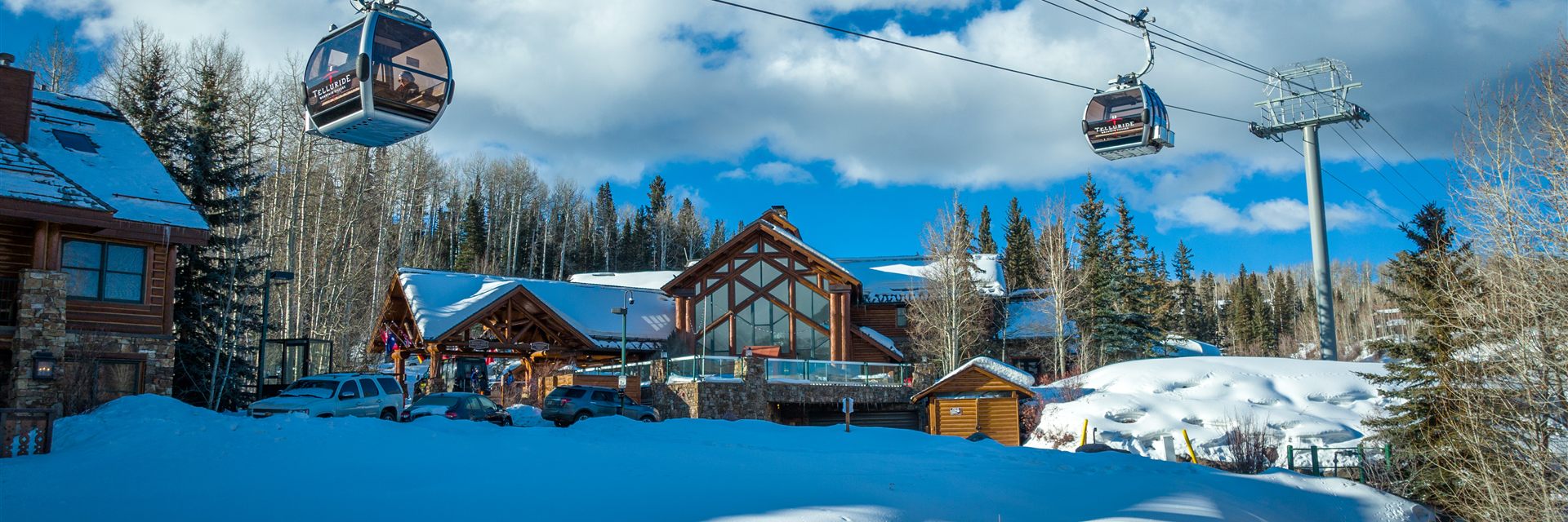 Gondola cabins passing over Mountain Lodge in the snow