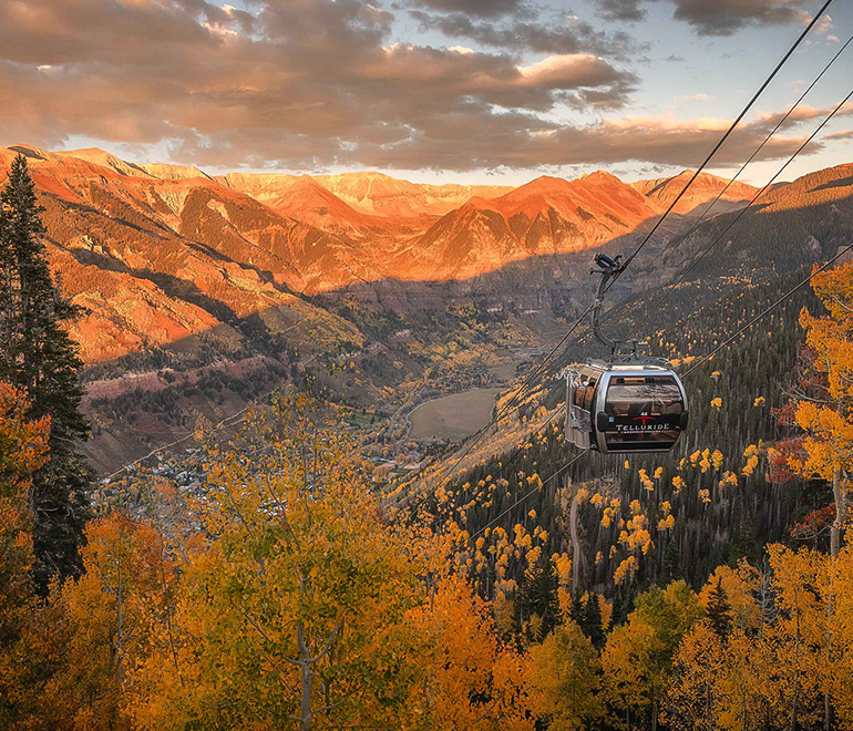 a cable car over a valley with mountains and trees
