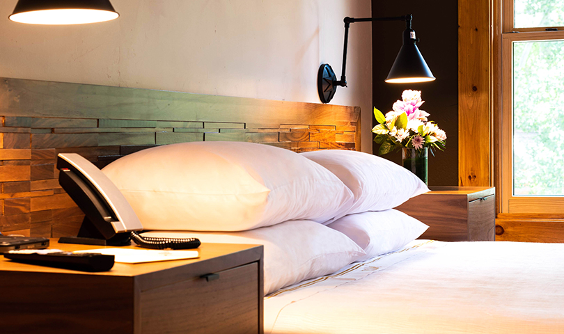 a bed with white pillows and a lamp on the side