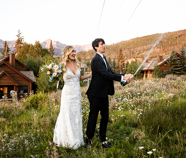 a bride and a groom spraying champagne outside