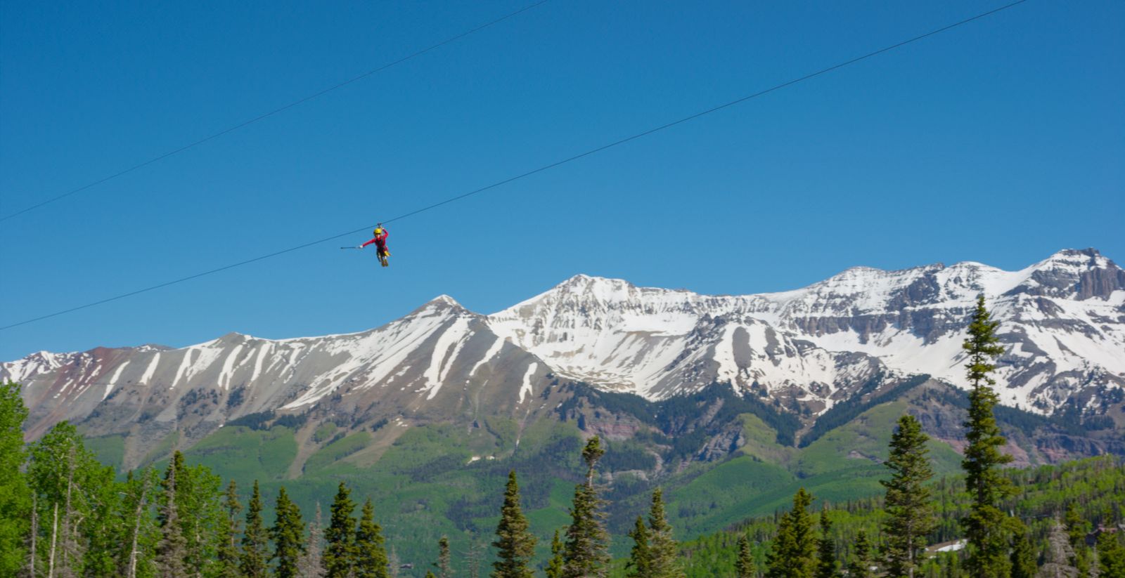 a person on a cable above a snowy mountain