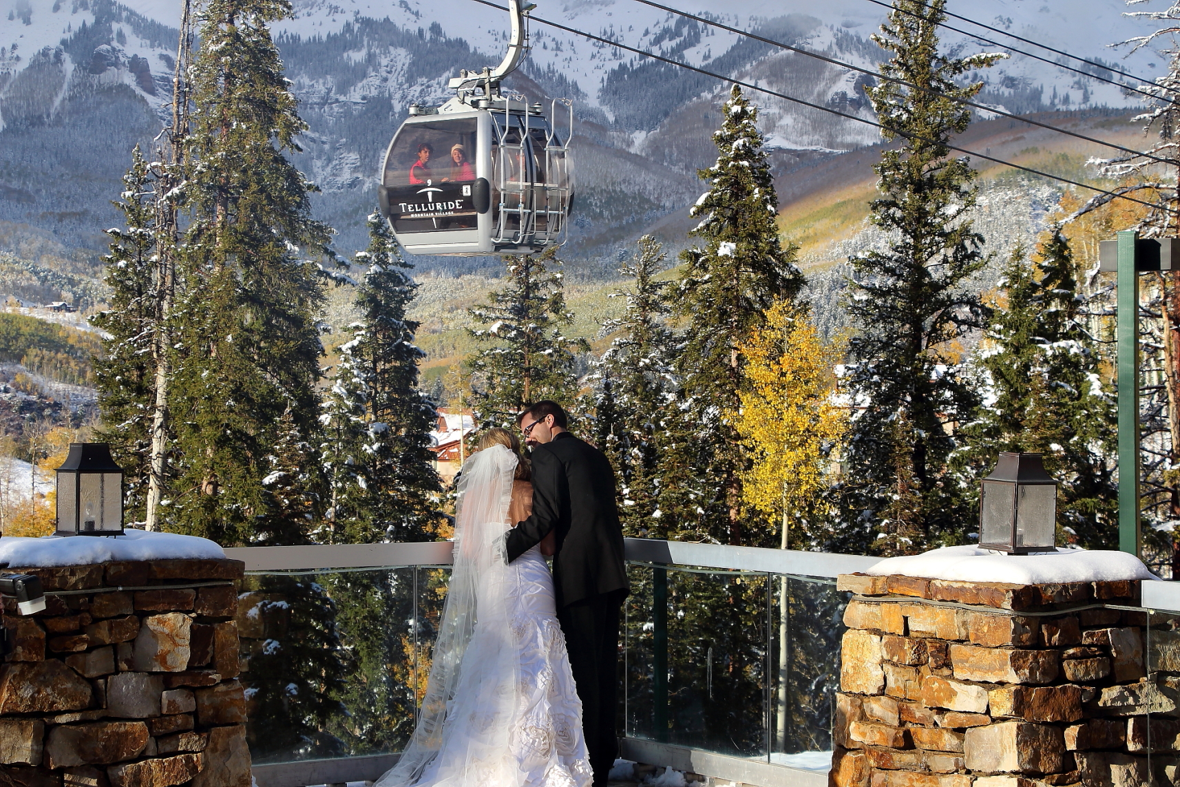 a bride and groom kissing on a deck with a cable car in the background