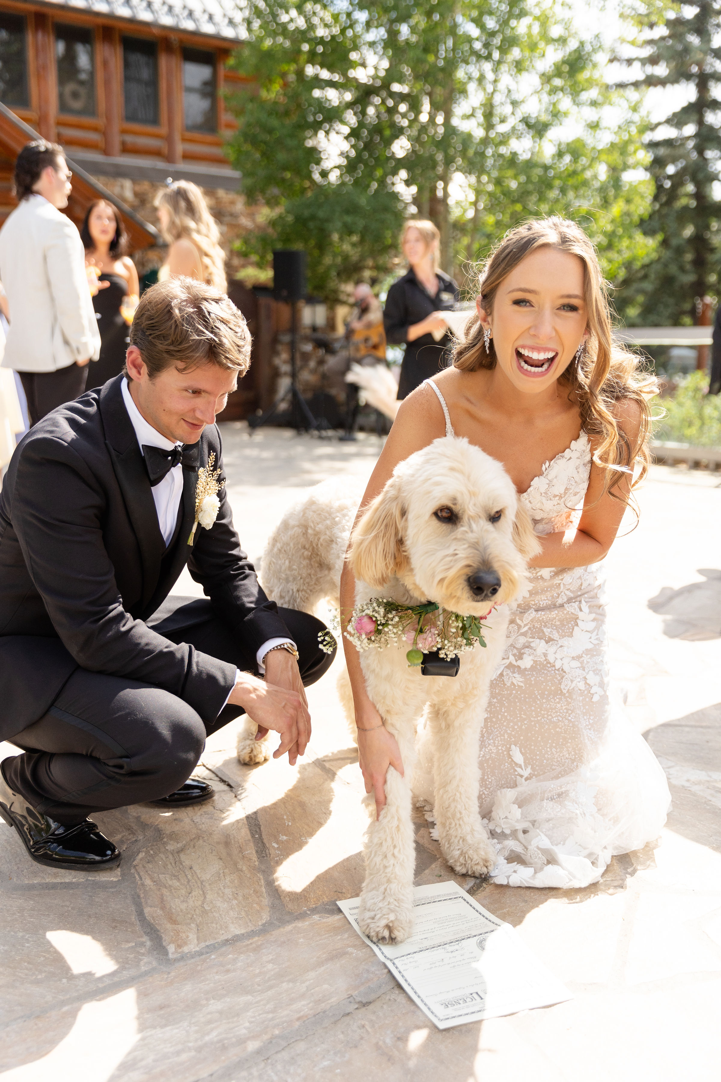 a man kneeling next to a woman in a wedding dress with a dog