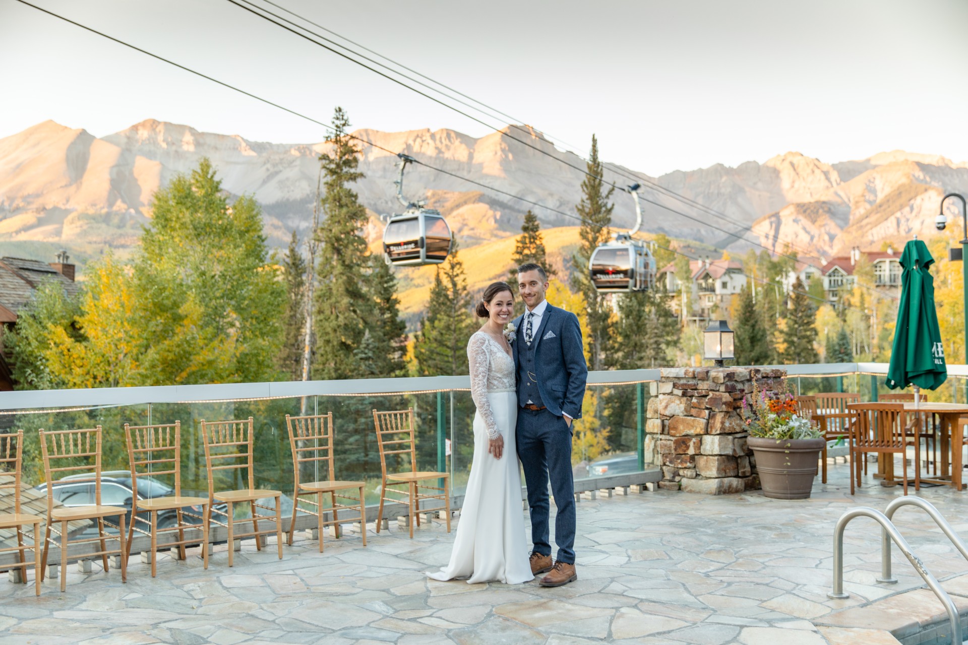 a man and woman standing on a patio with chairs and trees