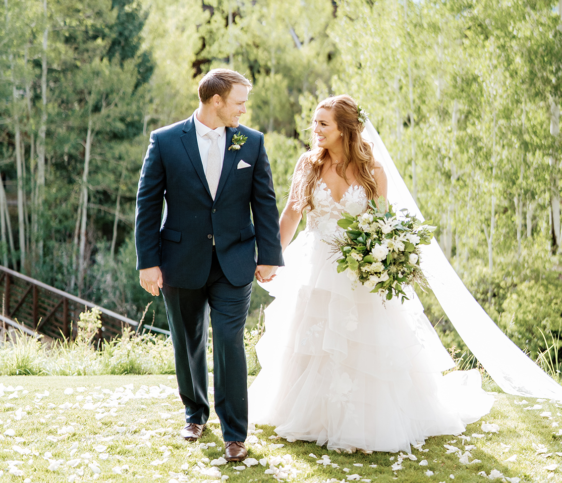 a man and woman walking down a path with flowers