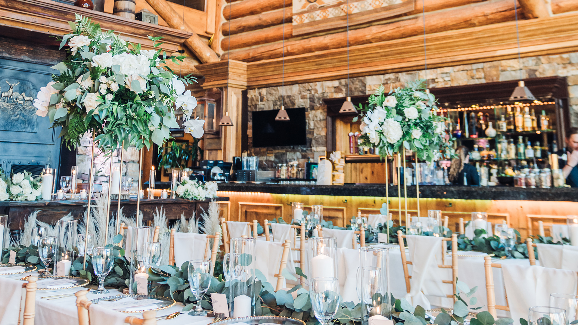 a room with tables and chairs with white flowers on them