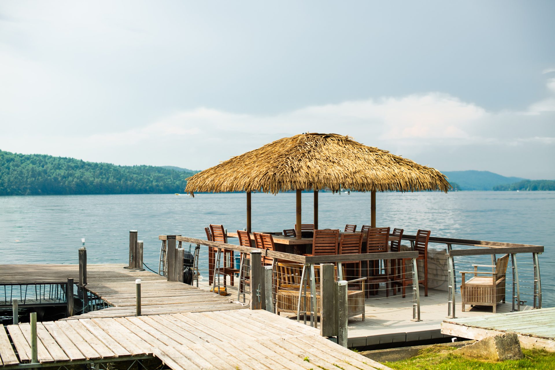 a dock with a thatched roof and chairs on it