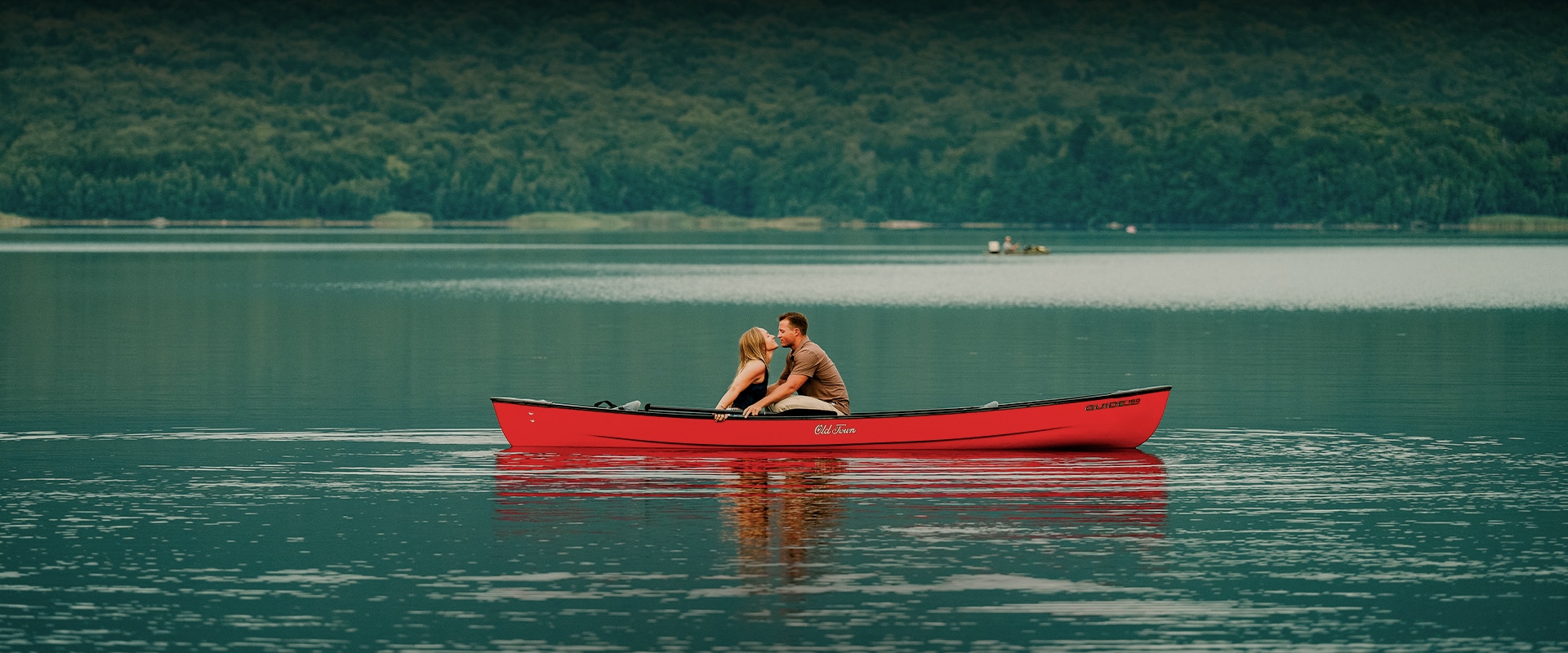 a man and woman kissing in a canoe on a lake