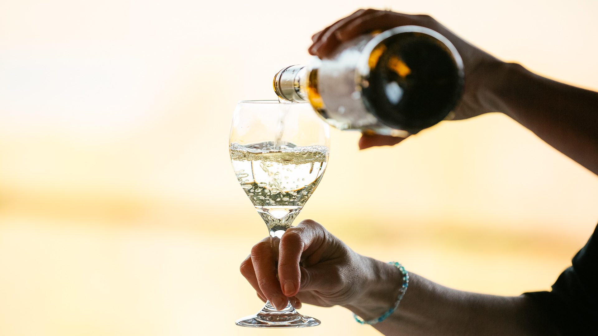 a person pouring a glass of wine