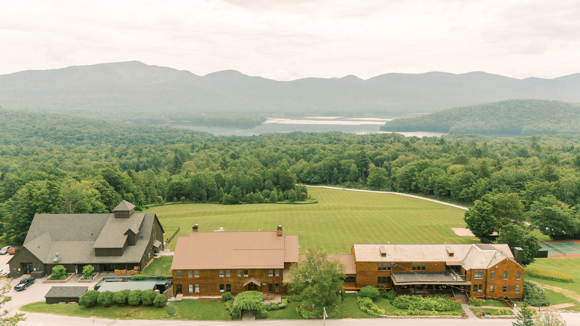 a large green field with trees and houses