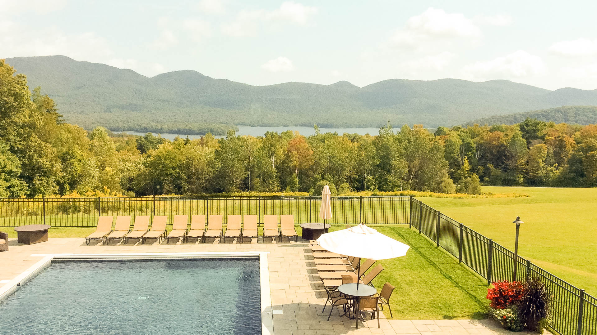 a pool with chairs and a fence and a pool in the background