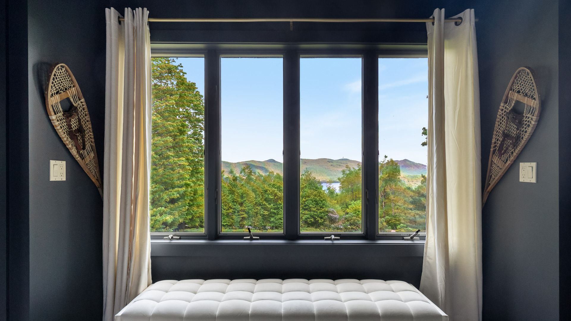 a window with white curtains and a bench