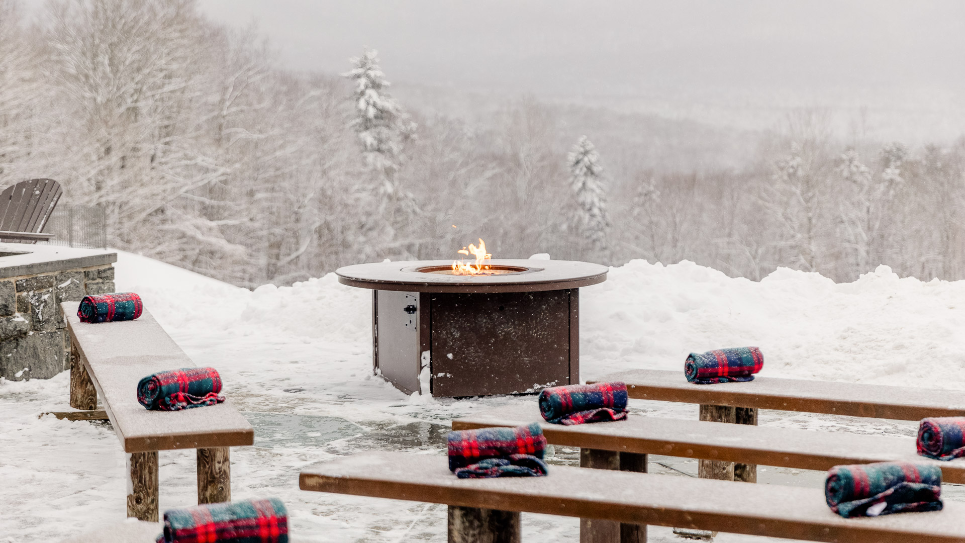 picnic tables with blankets on them in the snow