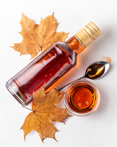 a bottle of liquid next to a cup of liquid and a spoon