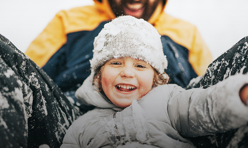 a child in a hat and jacket with snow on his head