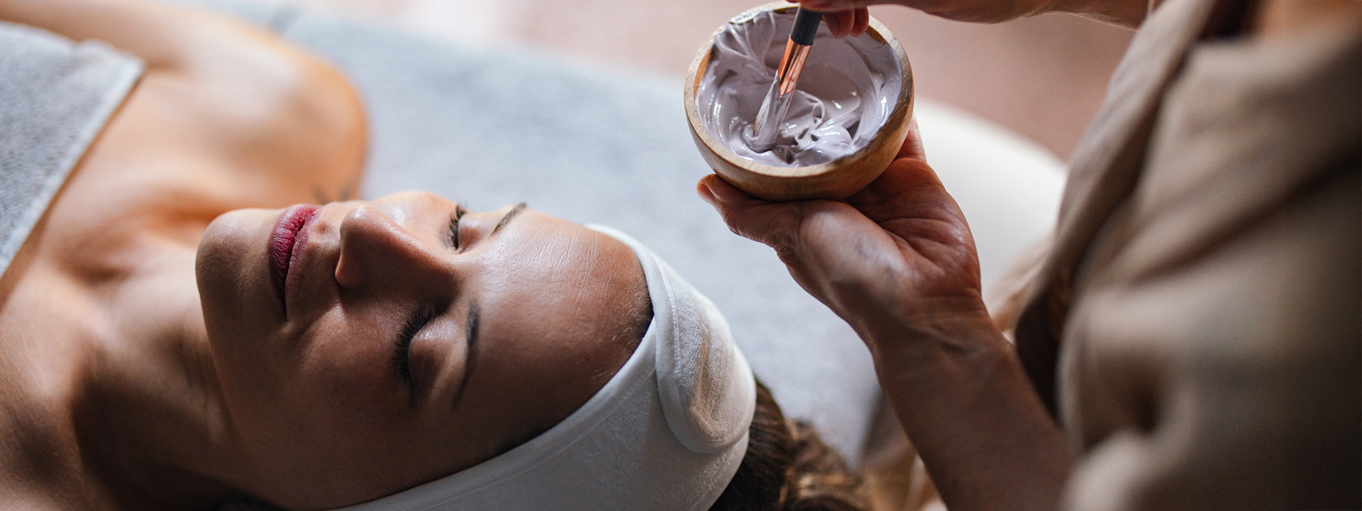 a person applying a mask on a woman's face