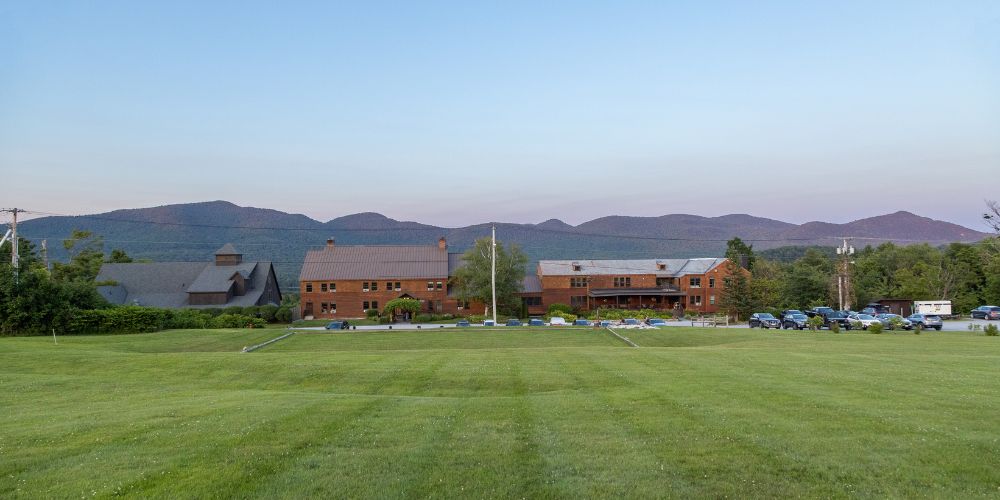 a large green field with buildings in the background