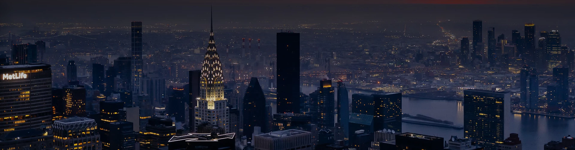 a city at night with a river and a tall building