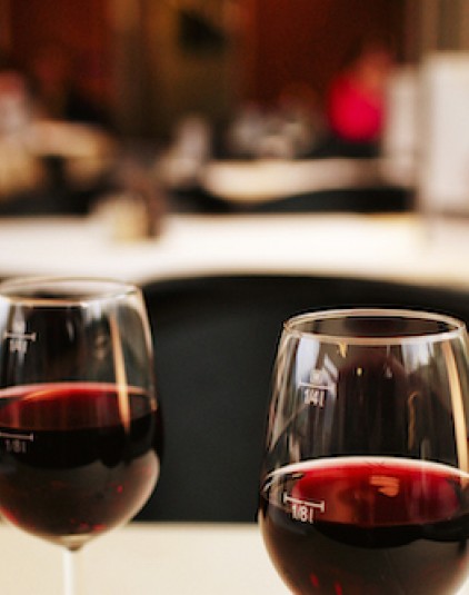 two glasses of red wine on white cloth covered table