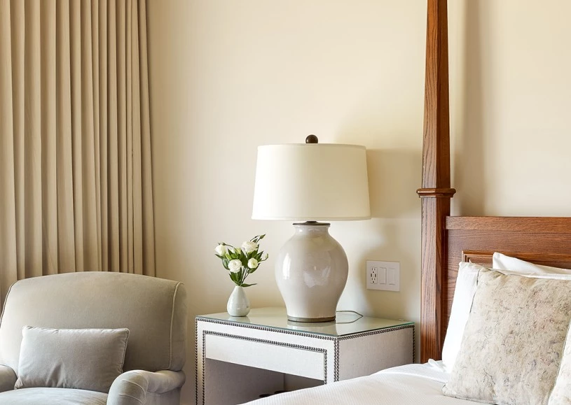Close up of an elegant bed next to a nightstand and a chair