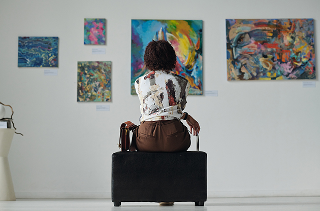 a woman sitting on a black bench looking at art