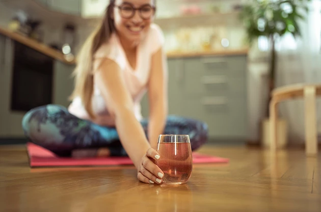 a woman sitting on the floor with a glass of liquid