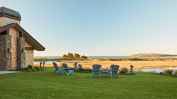 a lawn with chairs and a gazebo by the water