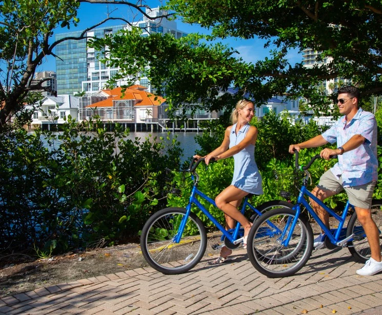 a man and woman riding bicycles on a path near water