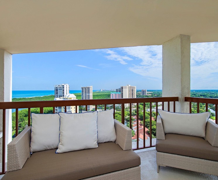 a couches on a balcony with a view of the ocean and city