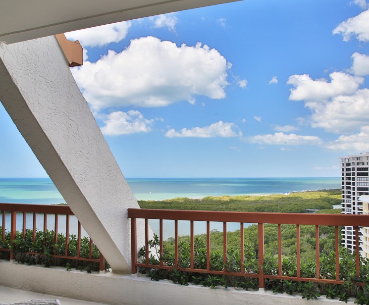 a balcony with a view of the ocean and trees