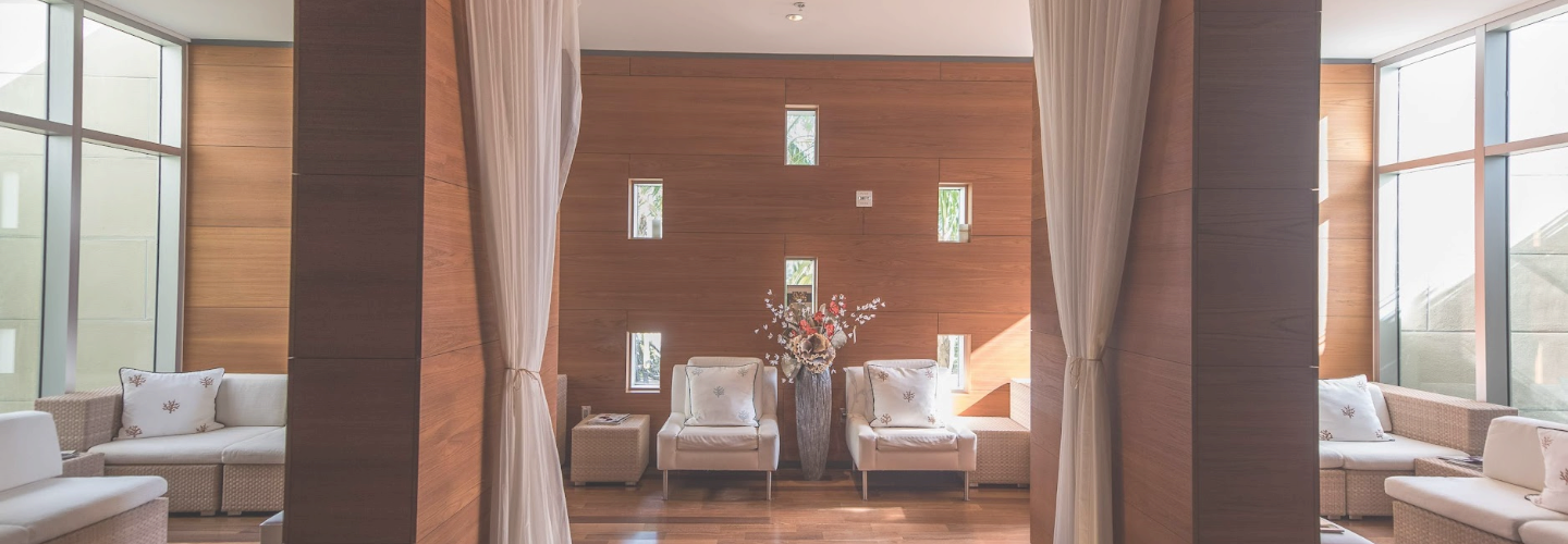 a room with white chairs and a vase of flowers