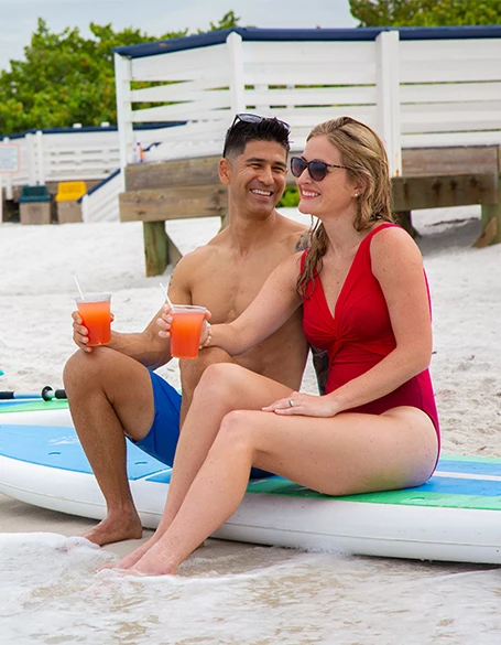 a man and woman sitting on a surfboard on a beach