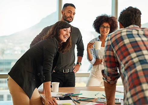 Men in women working around a table discussing projects