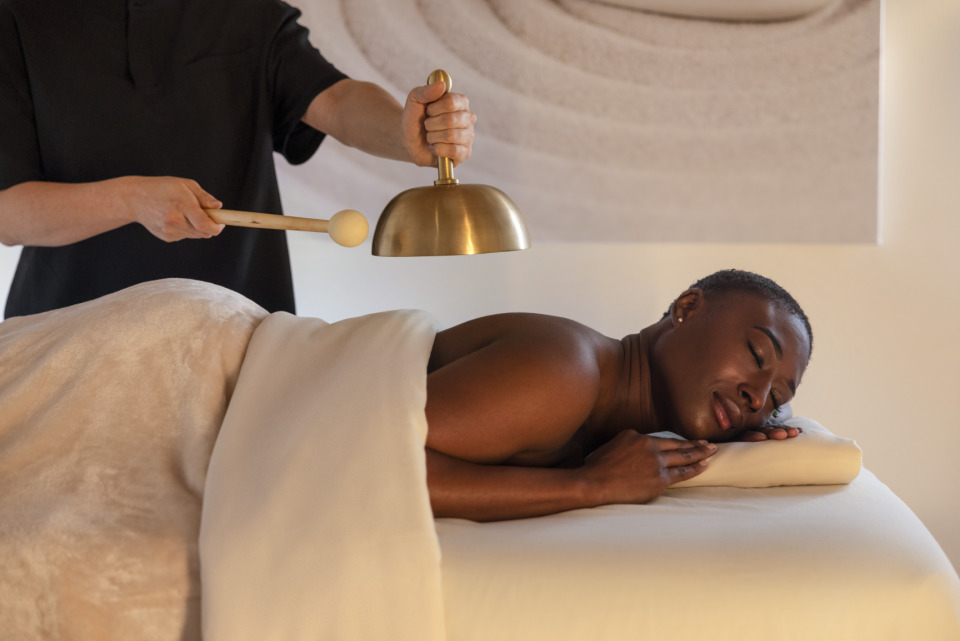 a person holding a bell over a woman lying on a bed