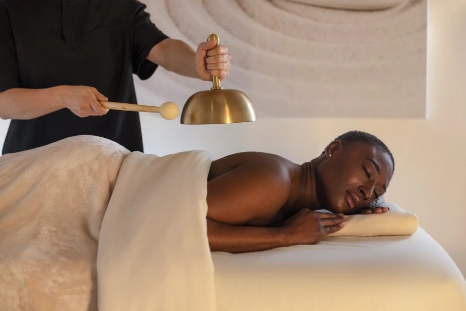 a person holding a bell over a woman lying on a bed