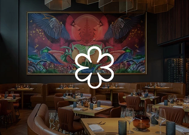 A restaurant dining area with tables, booths, and a large piece of artwork on the wall.
