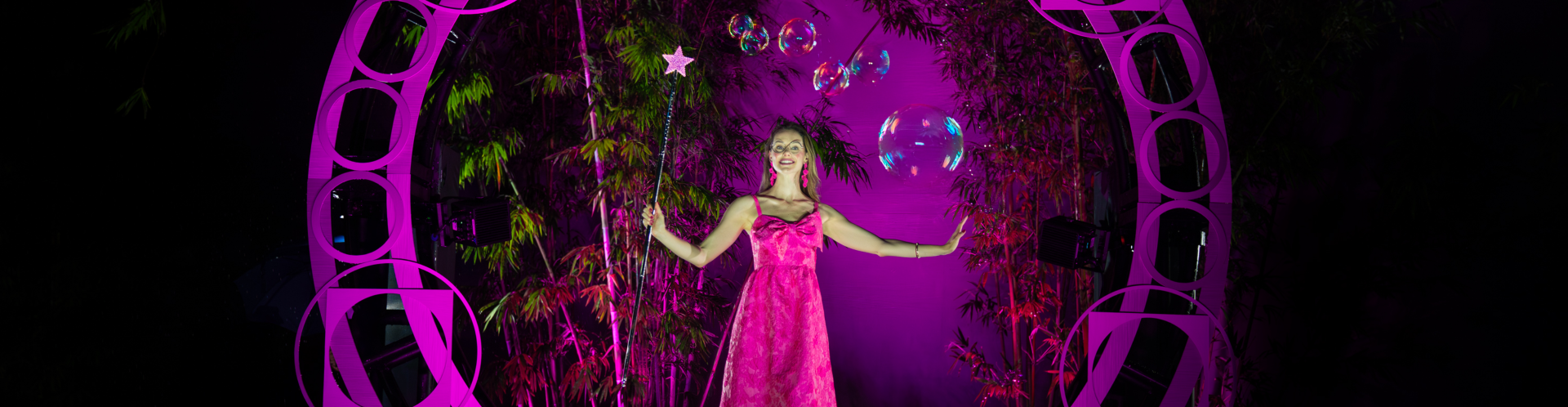 a woman in a pink dress holding a wand and bubbles
