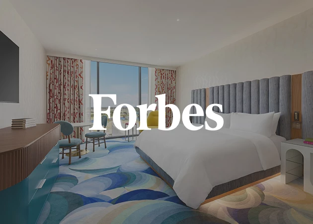A hotel room with a large bed, TV, table, chairs, and window