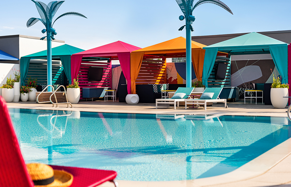 a pool with colorful umbrellas and lounge chairs