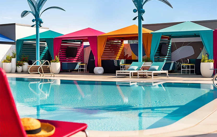 A swimming pool with lounge chairs and colorful canopies.