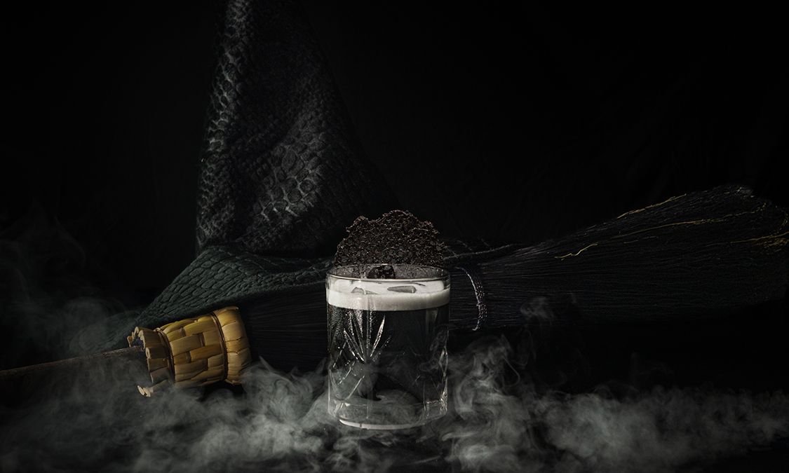 a glass with a liquid in it next to a broom