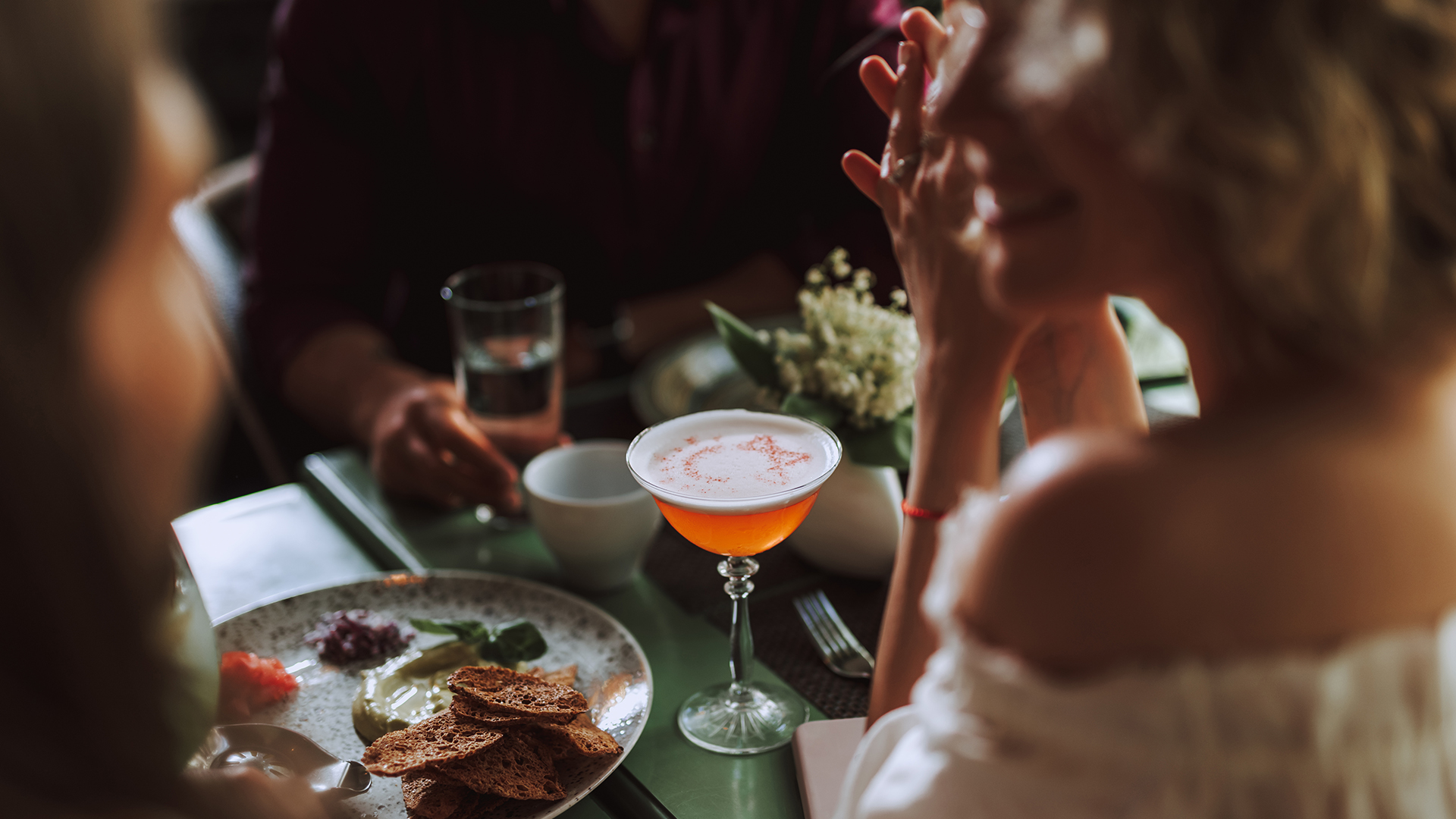 a woman sitting at a table with a drink and food