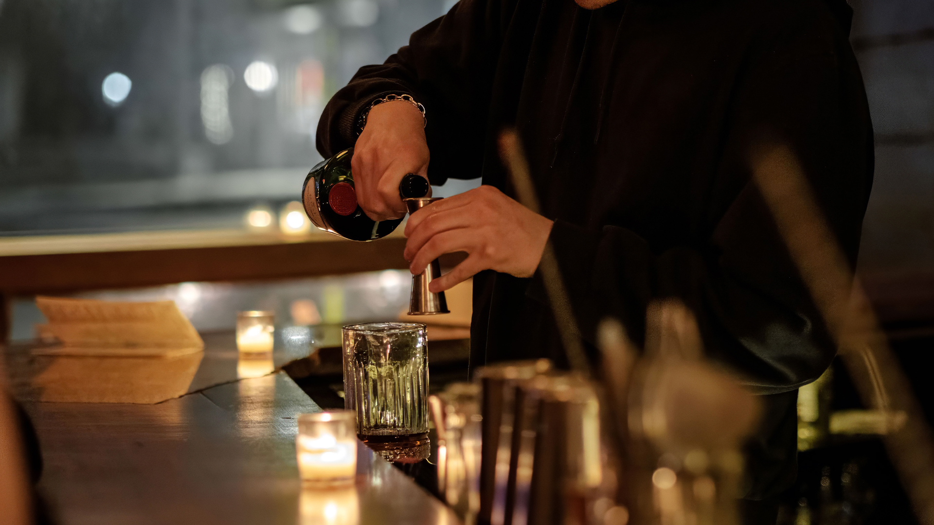 a person pouring a drink into a glass
