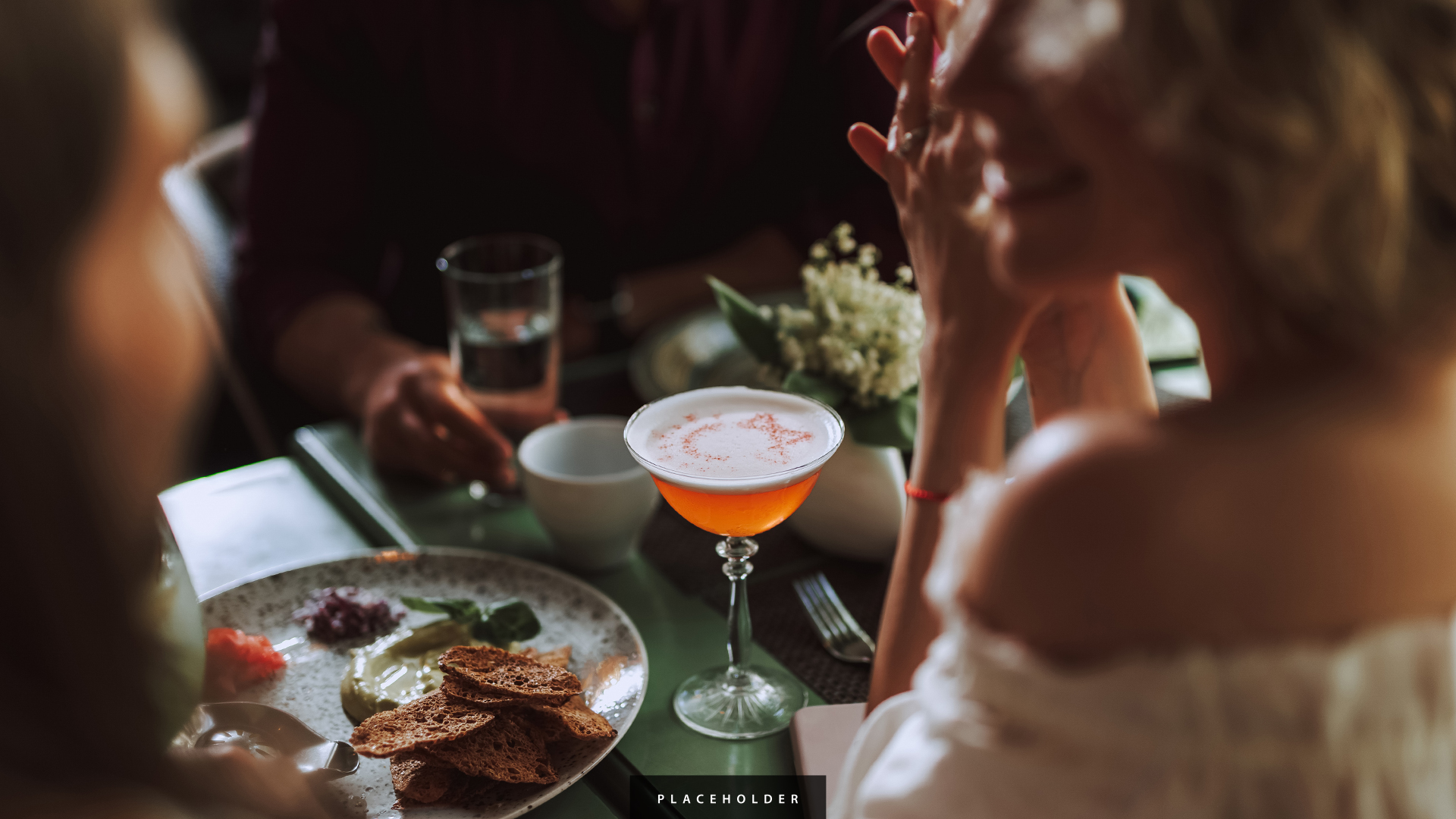 a woman clapping hands at a table with a plate of food
