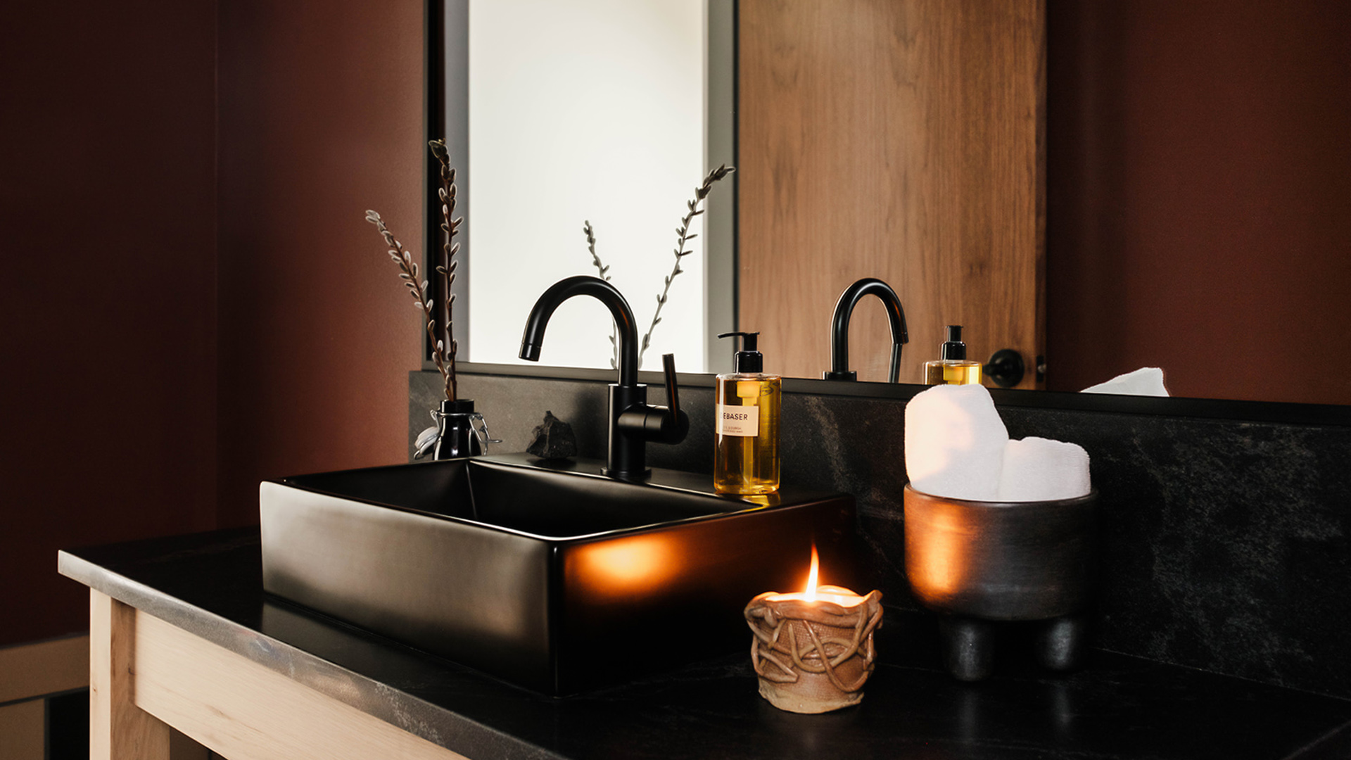 a black sink with a candle and a candle in front of it