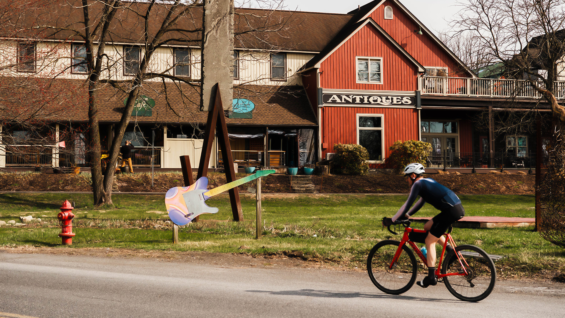 a man riding a bike on a road with a guitar in the air