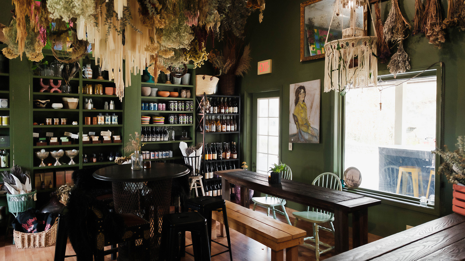 a room with a table and chairs and shelves with bottles and flowers