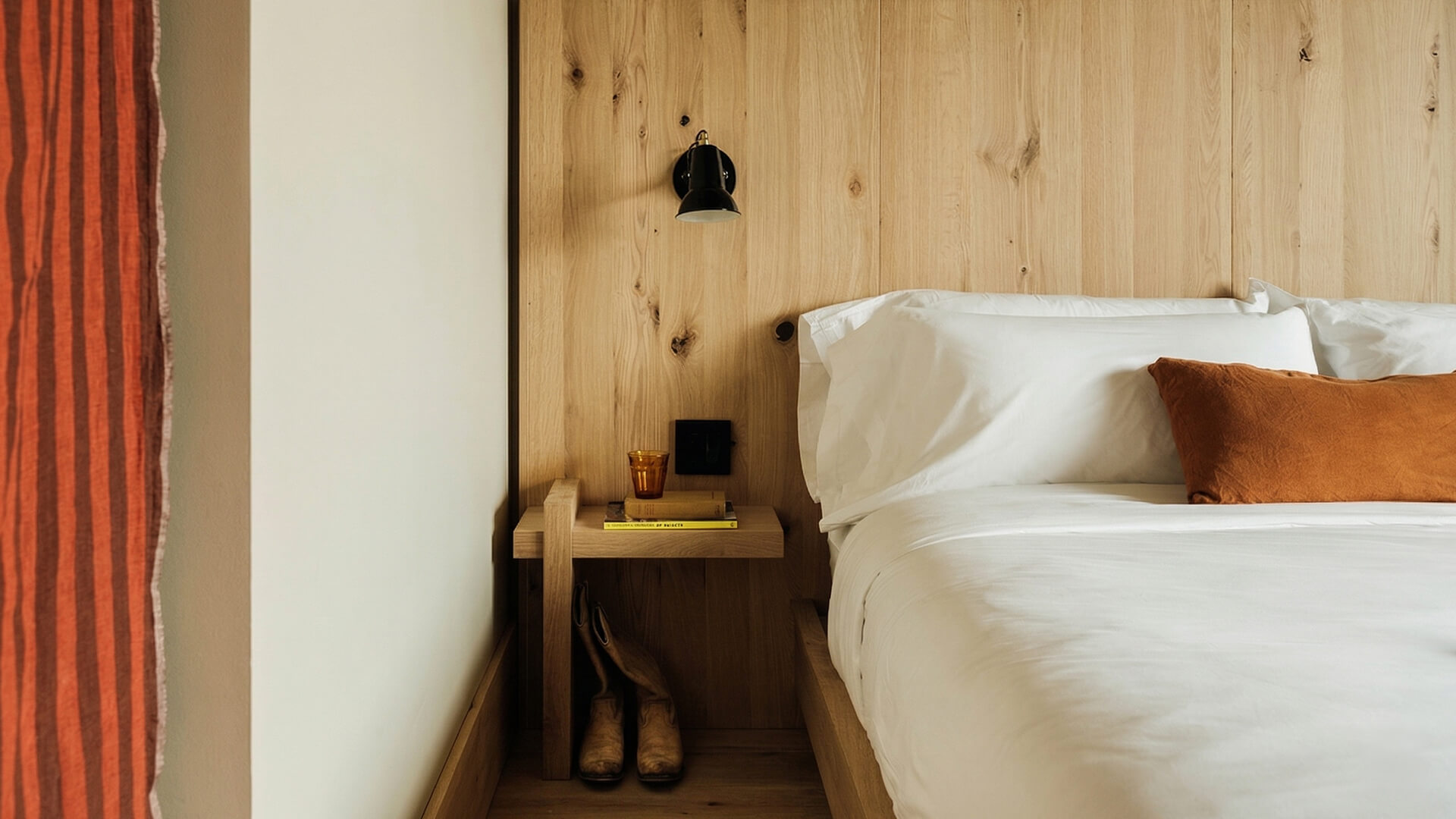 a bed with white sheets and a wooden wall